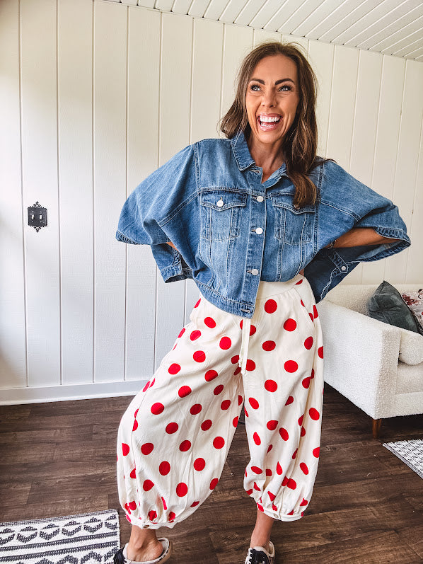 Soft, stretchy cream elastic drawstring waist pants with large red polka dots throughout, pockets and button cuffs for a balloon-like silhouette.
