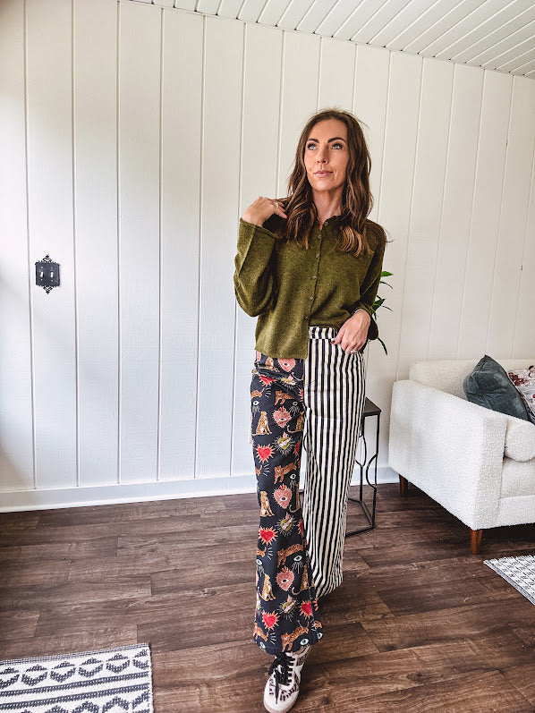 Lightweight denim-like non-stretch wide leg pants with elastic back waist, side and back pockets, button and zipper closure and black and cream stripes on one leg and funky leopard, heart, eye graphics on a black background on the other.