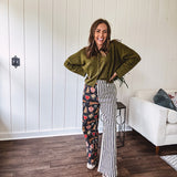 Lightweight denim-like non-stretch wide leg pants with elastic back waist, side and back pockets, button and zipper closure and black and cream stripes on one leg and funky leopard, heart, eye graphics on a black background on the other.