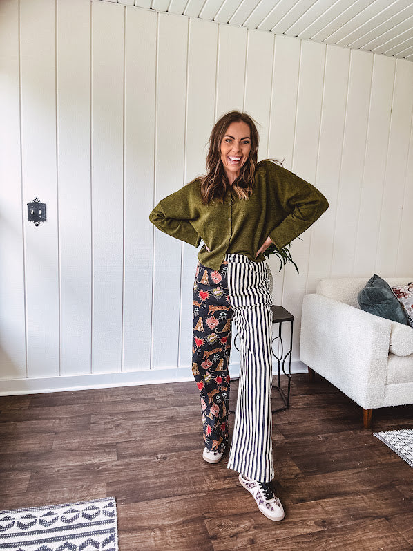 Lightweight denim-like non-stretch wide leg pants with elastic back waist, side and back pockets, button and zipper closure and black and cream stripes on one leg and funky leopard, heart, eye graphics on a black background on the other.