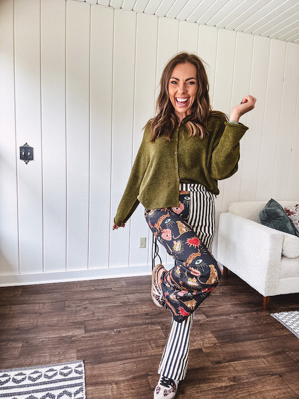 Lightweight denim-like non-stretch wide leg pants with elastic back waist, side and back pockets, button and zipper closure and black and cream stripes on one leg and funky leopard, heart, eye graphics on a black background on the other.