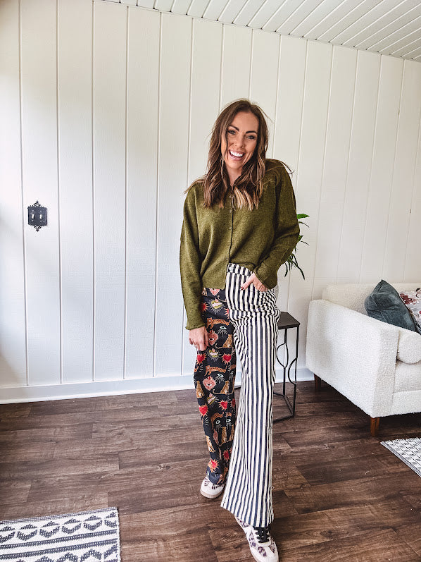 Lightweight denim-like non-stretch wide leg pants with elastic back waist, side and back pockets, button and zipper closure and black and cream stripes on one leg and funky leopard, heart, eye graphics on a black background on the other.