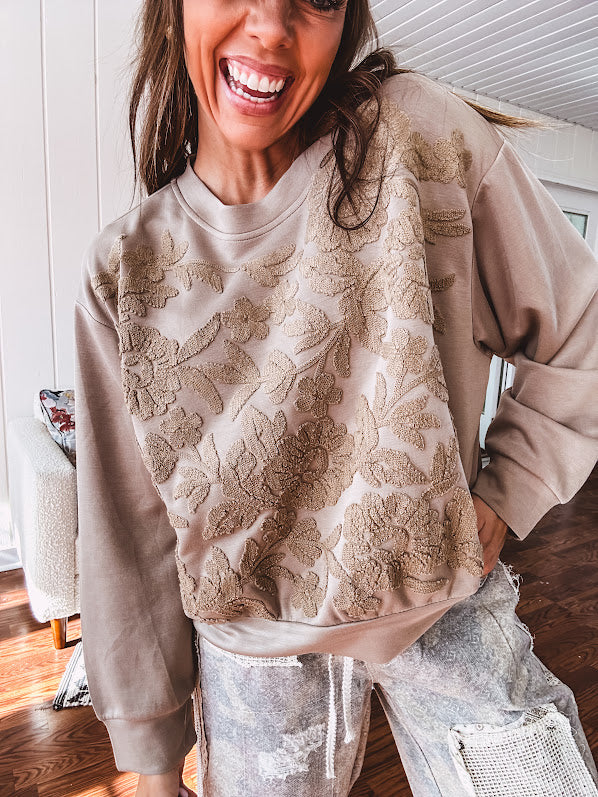 Taupe crew neck pullover with matching floral embroidery on the front.