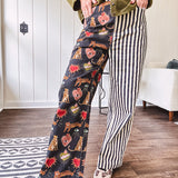 Lightweight denim-like non-stretch wide leg pants with elastic back waist, side and back pockets, button and zipper closure and black and cream stripes on one leg and funky leopard, heart, eye graphics on a black background on the other.