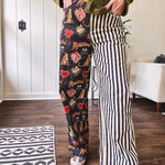 Lightweight denim-like non-stretch wide leg pants with elastic back waist, side and back pockets, button and zipper closure and black and cream stripes on one leg and funky leopard, heart, eye graphics on a black background on the other.