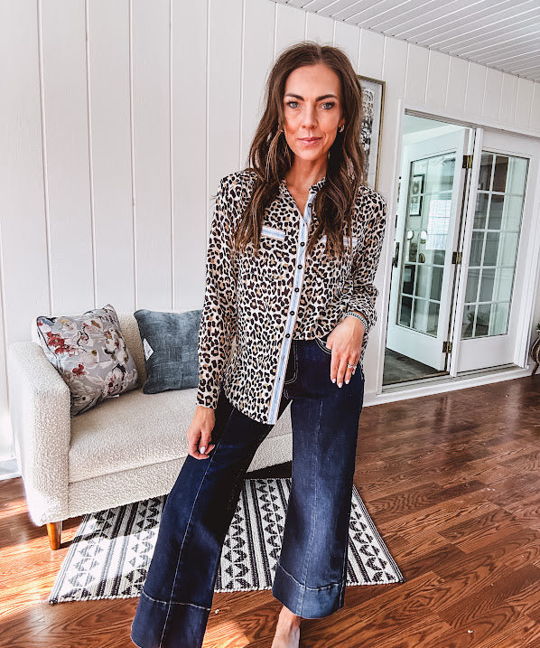 Thin, lightweight long sleeved button down top with leo print and contrasting blue, tan, white and red striping at the buttons and pockets.