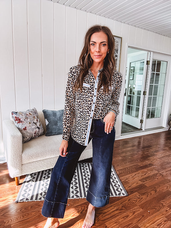 Thin, lightweight long sleeved button down top with leo print and contrasting blue, tan, white and red striping at the buttons and pockets.