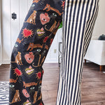 Lightweight denim-like non-stretch wide leg pants with elastic back waist, side and back pockets, button and zipper closure and black and cream stripes on one leg and funky leopard, heart, eye graphics on a black background on the other.