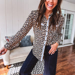 Thin, lightweight long sleeved button down top with leo print and contrasting blue, tan, white and red striping at the buttons and pockets.