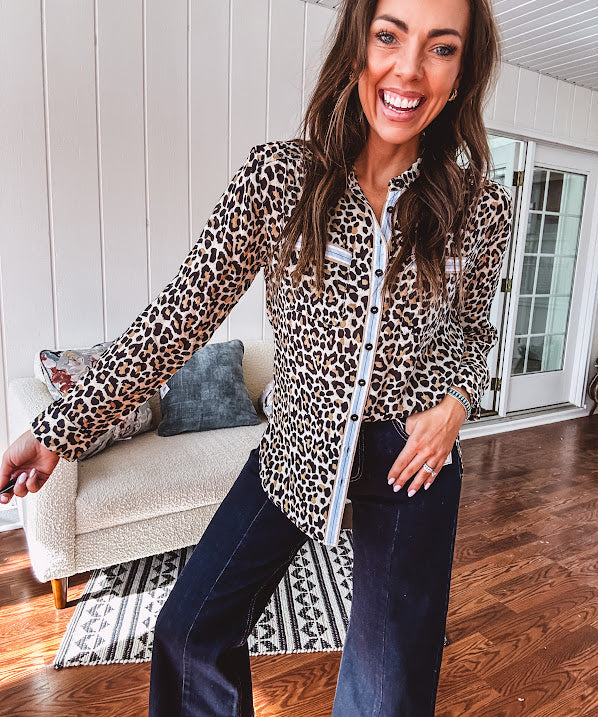 Thin, lightweight long sleeved button down top with leo print and contrasting blue, tan, white and red striping at the buttons and pockets.