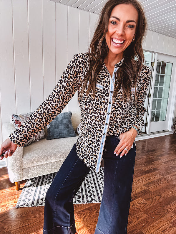 Thin, lightweight long sleeved button down top with leo print and contrasting blue, tan, white and red striping at the buttons and pockets.