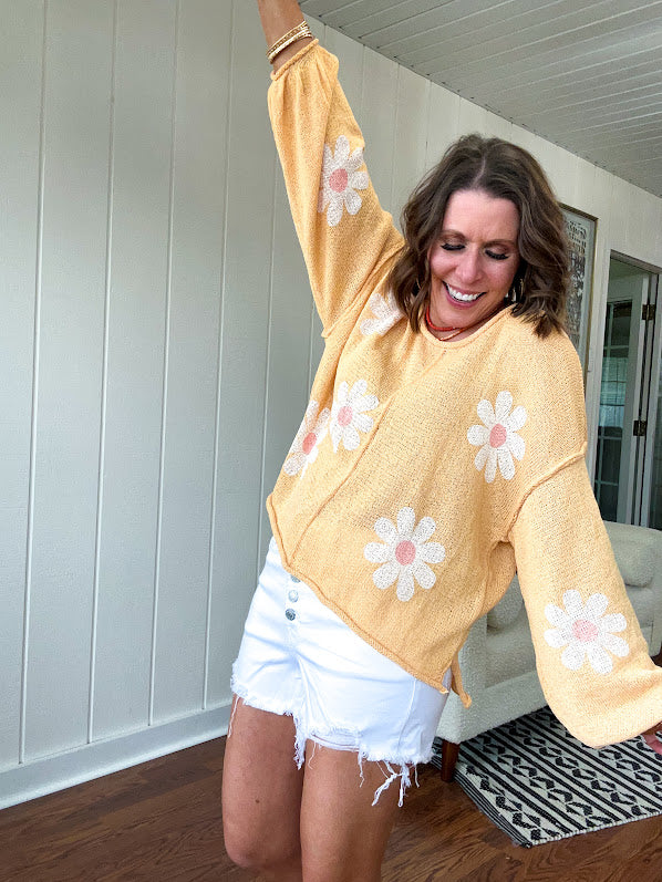 Soft, lightweight, nearly sheer knit pullover  with long sleeves, exposed seams at the shoulders and down the center with large daisy florals throughout. Available in multiple colors.