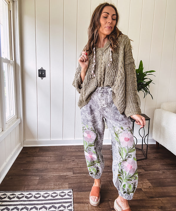 Lightweight washed black joggers with elastic back, floral button down closure and pink and green oversized floral embroidery down the front of both legs.