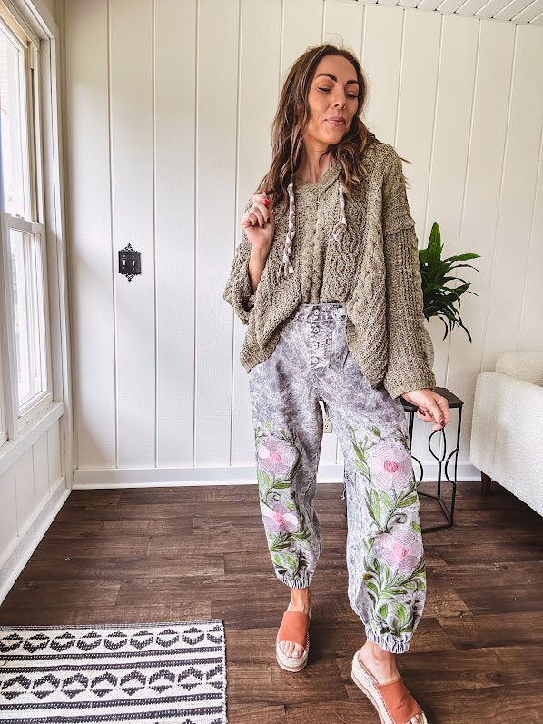 Lightweight washed black joggers with elastic back, floral button down closure and pink and green oversized floral embroidery down the front of both legs.