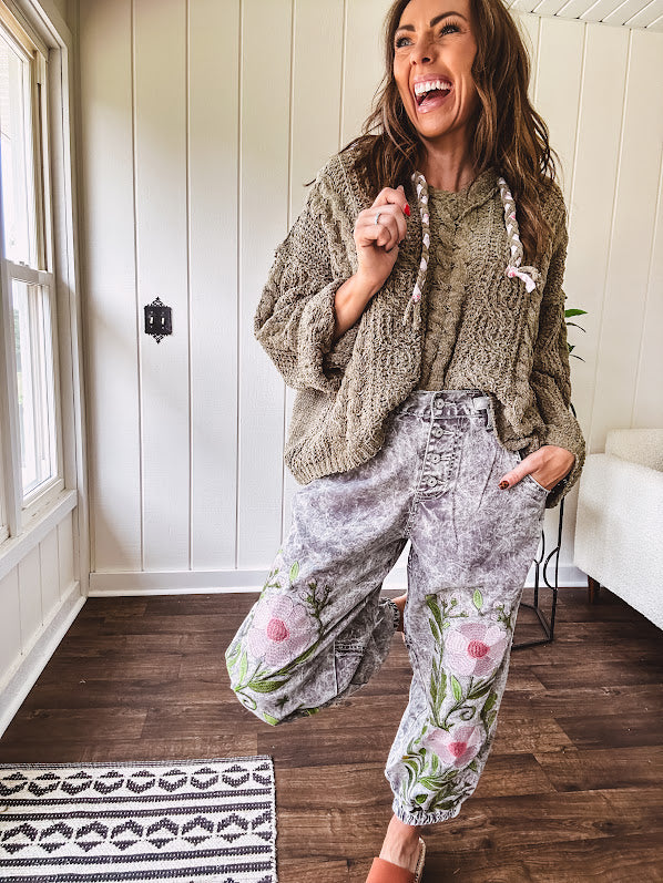 Lightweight washed black joggers with elastic back, floral button down closure and pink and green oversized floral embroidery down the front of both legs.