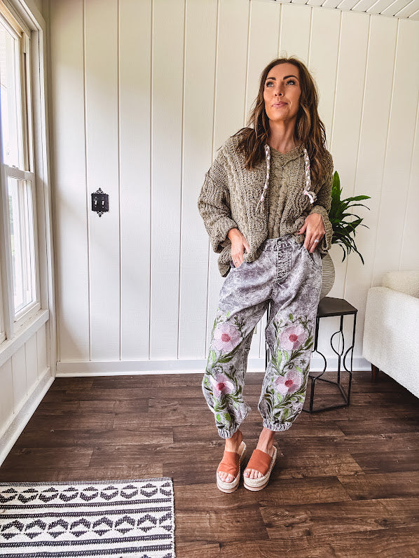 Lightweight washed black joggers with elastic back, floral button down closure and pink and green oversized floral embroidery down the front of both legs.