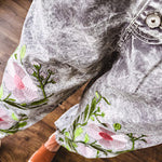 Lightweight washed black joggers with elastic back, floral button down closure and pink and green oversized floral embroidery down the front of both legs.