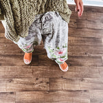 Lightweight washed black joggers with elastic back, floral button down closure and pink and green oversized floral embroidery down the front of both legs.
