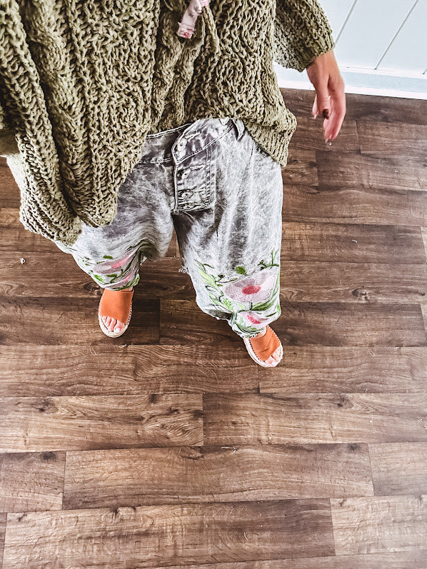 Lightweight washed black joggers with elastic back, floral button down closure and pink and green oversized floral embroidery down the front of both legs.