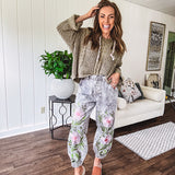 Lightweight washed black joggers with elastic back, floral button down closure and pink and green oversized floral embroidery down the front of both legs.