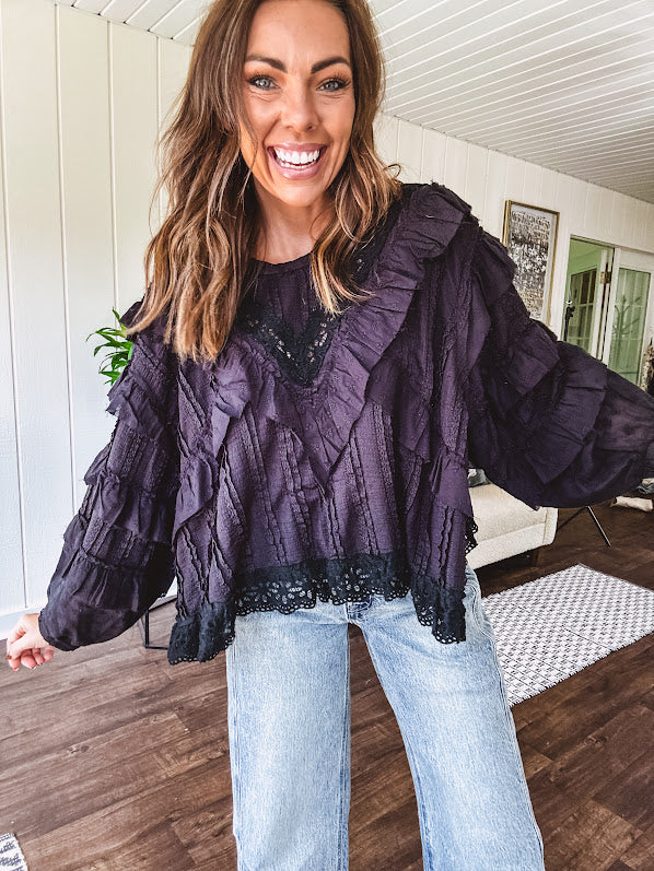Black long sleeved blouse with lace and eyelet ruffle detail throughout.
