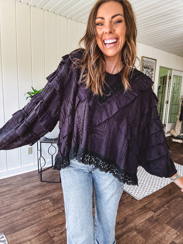 Black long sleeved blouse with lace and eyelet ruffle detail throughout.