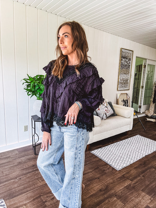 Black long sleeved blouse with lace and eyelet ruffle detail throughout.