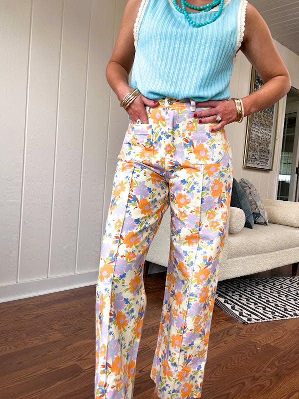 Cotton button and zipper closure bright floral pants with seams down the front of both legs and front and back pockets.