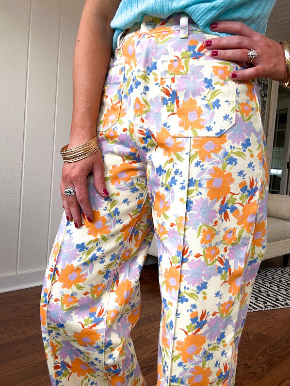 Cotton button and zipper closure bright floral pants with seams down the front of both legs and front and back pockets.