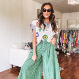 Lightweight green washed pinktuck front ultra wide leg pants with button front and drawstring.