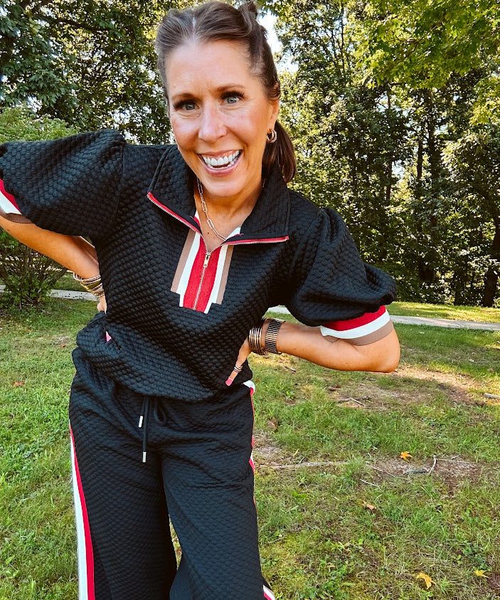 Black quilted top with cream, red and taupe stripes along the 1/4 zip neckline and cuffs with puff sleeves.