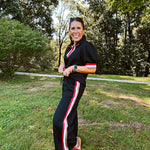 Black quilted short sleeved top with puff sleeves, 1/4 zip and taupe, red and cream striping detail at the neck and cuffs.