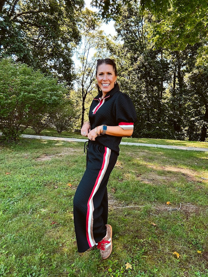 Wide leg black quilted pants with drawstring elastic waist and cream, red and taupe stripes down the legs.