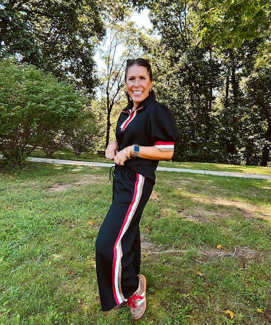 Wide leg black quilted pants with drawstring elastic waist and cream, red and taupe stripes down the legs.