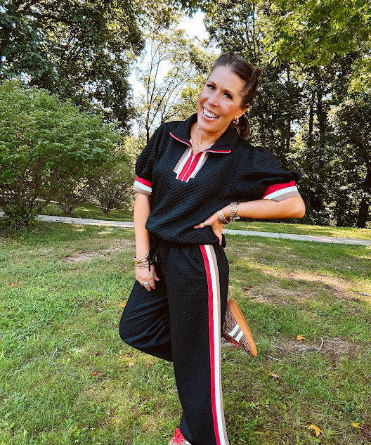 Wide leg black quilted pants with drawstring elastic waist and cream, red and taupe stripes down the legs.