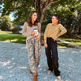 Lightweight cotton balloon pants in gray with golden florals throughout, front pleats and lace trimmed pockets. Button and zipper closure with elastic back.