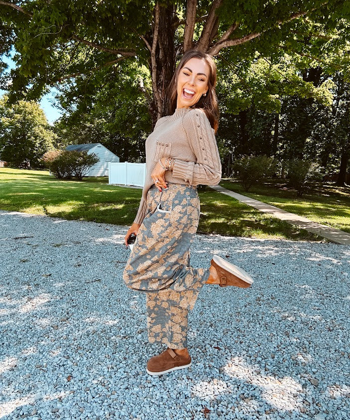 Lightweight cotton balloon pants in gray with golden florals throughout, front pleats and lace trimmed pockets. Button and zipper closure with elastic back.
