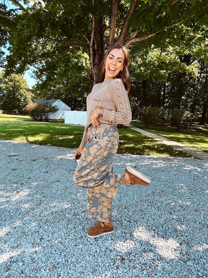 Lightweight cotton balloon pants in gray with golden florals throughout, front pleats and lace trimmed pockets. Button and zipper closure with elastic back.