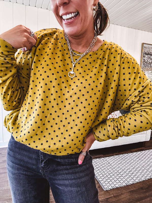 Thin, lightweight mustard long sleeved top with black polka dots throughout and elastic bubble hem.