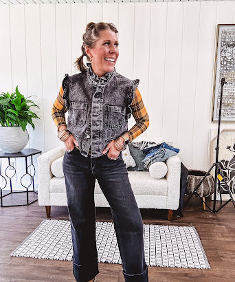 Washed black denim vest with ruffles at collar and sleeves, front pockets and silver buttons down the front.
