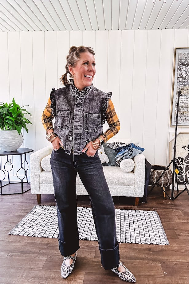 Washed black denim vest with ruffles at collar and sleeves, front pockets and silver buttons down the front.