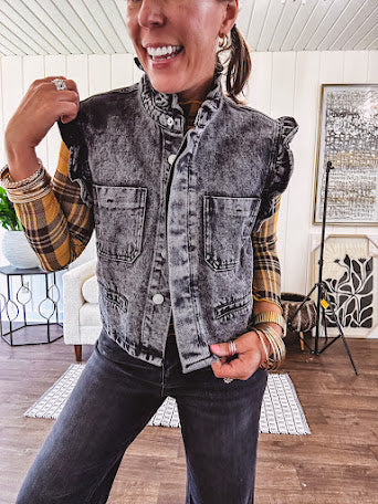 Washed black denim vest with ruffles at collar and sleeves, front pockets and silver buttons down the front.