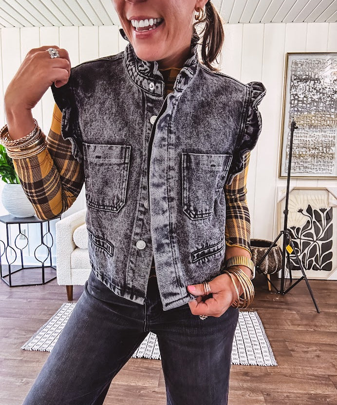 Washed black denim vest with ruffles at collar and sleeves, front pockets and silver buttons down the front.