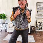 Washed black denim vest with ruffles at collar and sleeves, front pockets and silver buttons down the front.