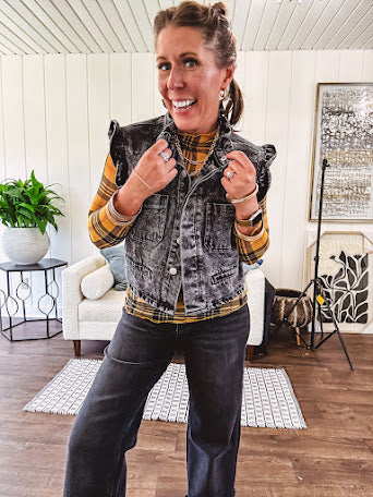 Washed black denim vest with ruffles at collar and sleeves, front pockets and silver buttons down the front.