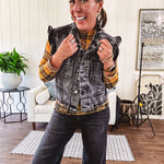Washed black denim vest with ruffles at collar and sleeves, front pockets and silver buttons down the front.