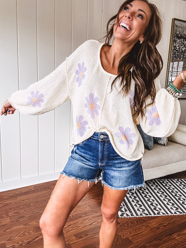 Soft, lightweight, nearly sheer knit pullover  with long sleeves, exposed seams at the shoulders and down the center with large daisy florals throughout. Available in multiple colors.