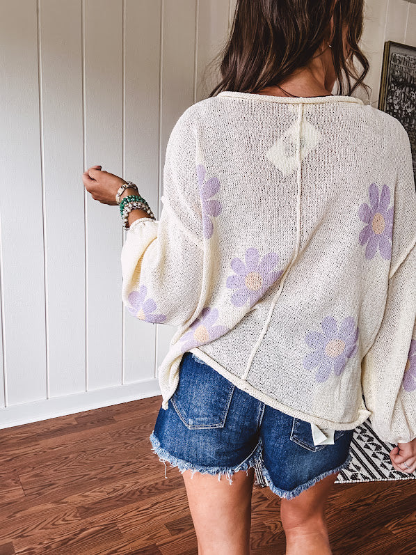 Soft, lightweight, nearly sheer knit pullover  with long sleeves, exposed seams at the shoulders and down the center with large daisy florals throughout. Available in multiple colors.