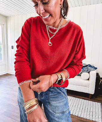 Light weight red ribbed long sleeved top with white whip stitching at the round neck and cuffs.