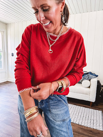 Light weight red ribbed long sleeved top with white whip stitching at the round neck and cuffs.